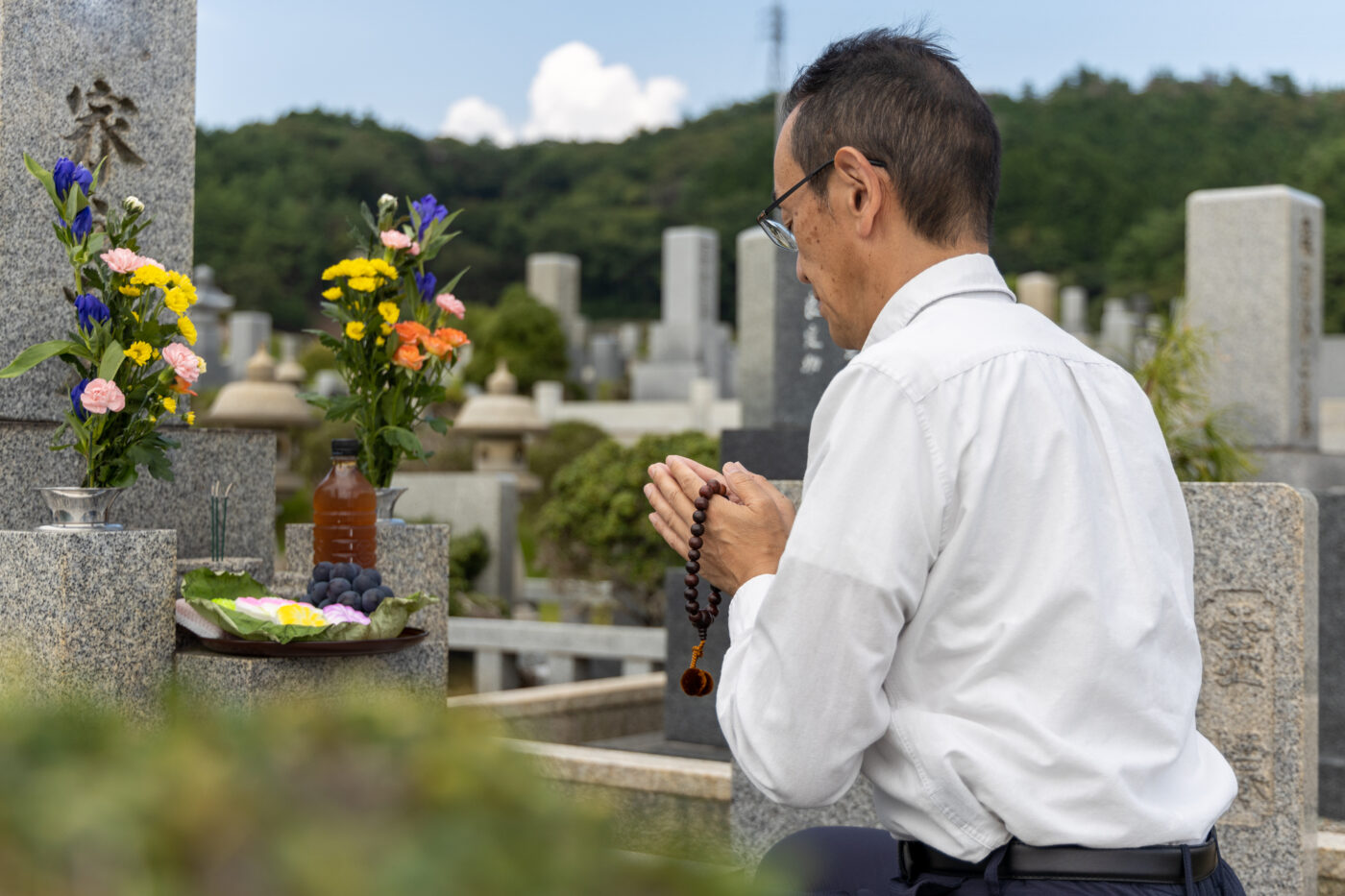 お墓の前で手を合わせる男性